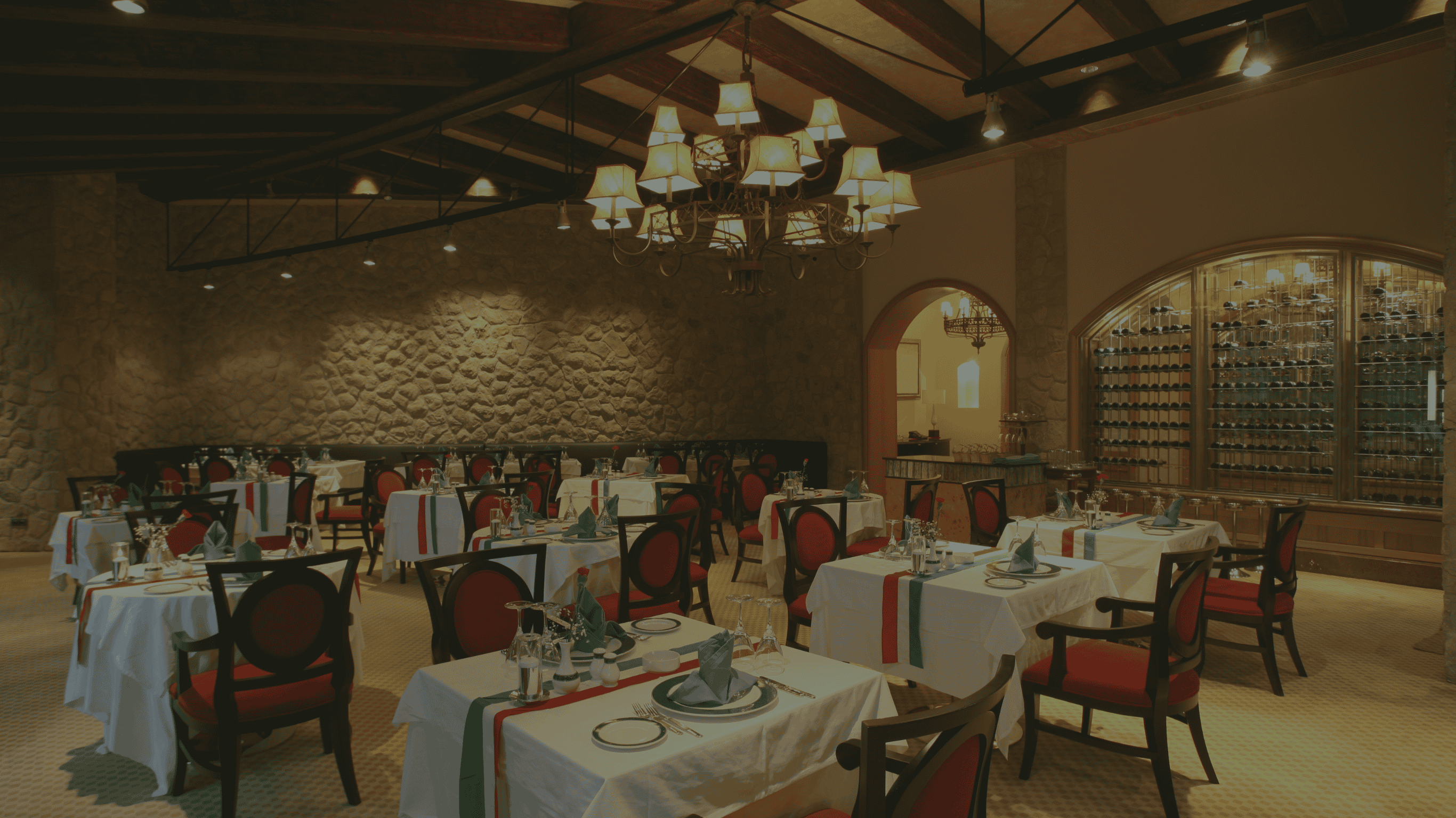 The background shows the interior of Third Eye Restaurant, featuring a dining space with a high wooden beam ceiling and a large chandelier with multiple lamp shades. The dining area has neatly arranged tables with white tablecloths and formal place settings. A wine rack is visible along the wall at Third Eye Windsor, 515 George St, South Windsor NSW 2756.